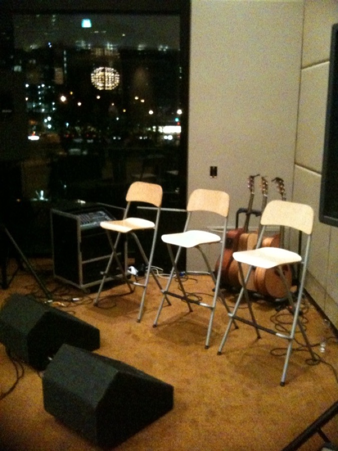 Three stools with guitars in front of a city night window